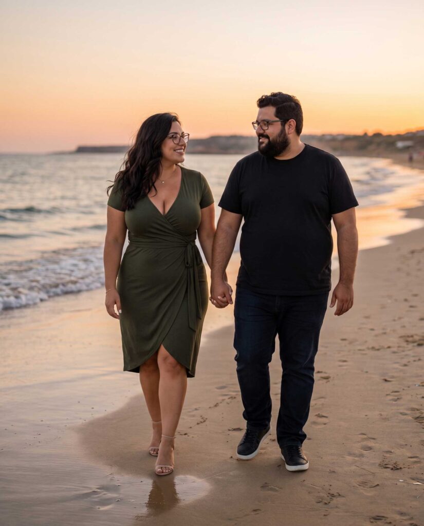 Anna und Karl gehen Hand in Hand bei Sonnenuntergang am Strand entlang.